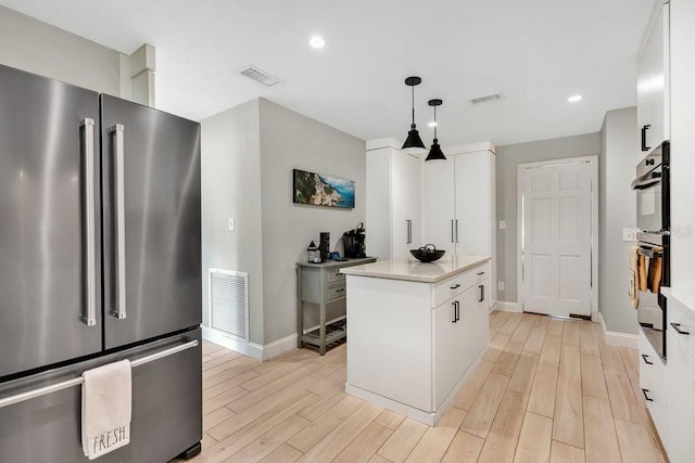 kitchen with high quality fridge, visible vents, and light wood-style floors