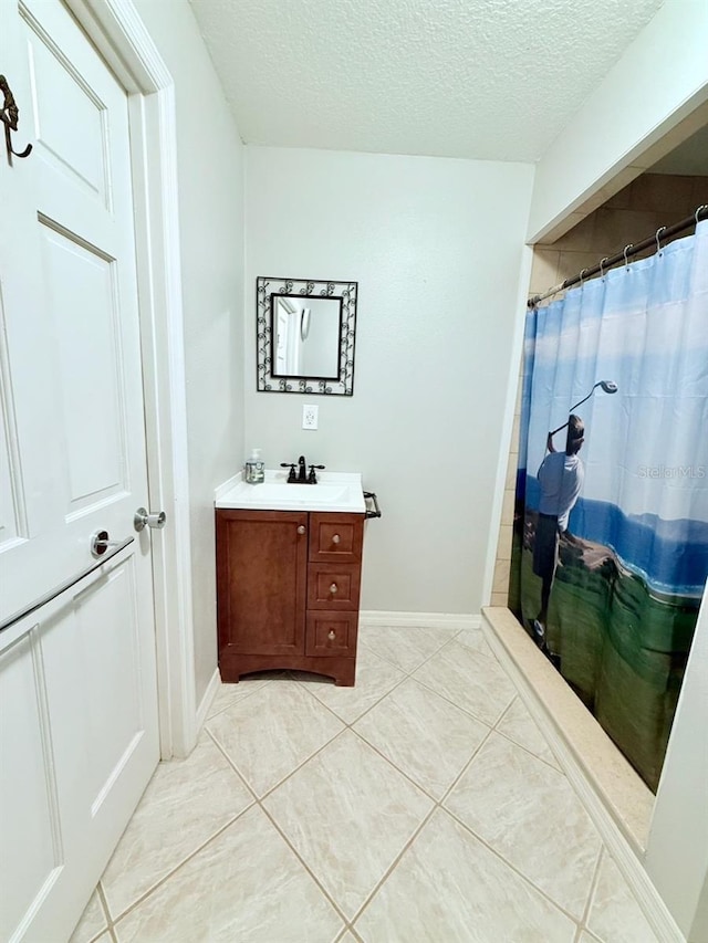 bathroom with a textured ceiling, curtained shower, tile patterned flooring, and vanity