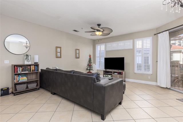 living room featuring light tile patterned floors and ceiling fan with notable chandelier