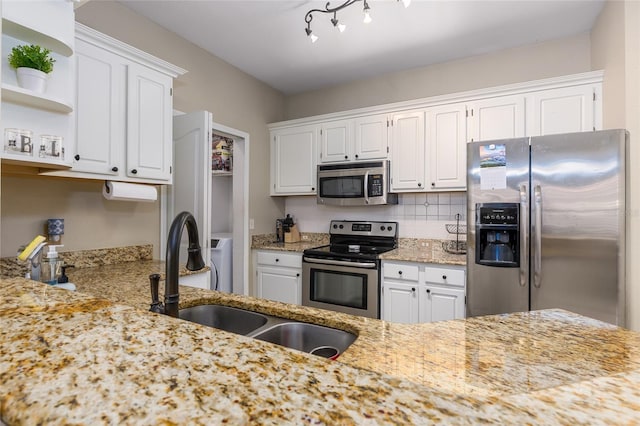 kitchen featuring decorative backsplash, light stone countertops, stainless steel appliances, sink, and white cabinetry