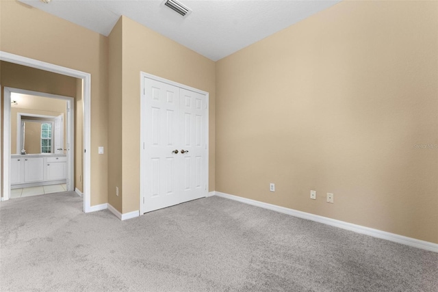 unfurnished bedroom featuring light carpet and a closet