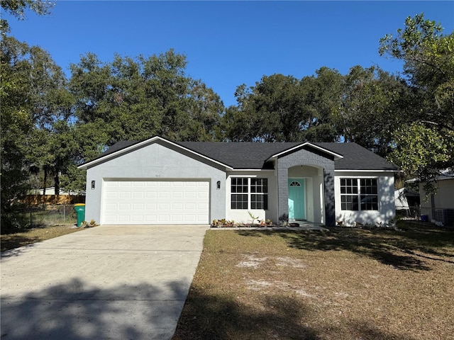 single story home with stucco siding, an attached garage, fence, driveway, and a front lawn