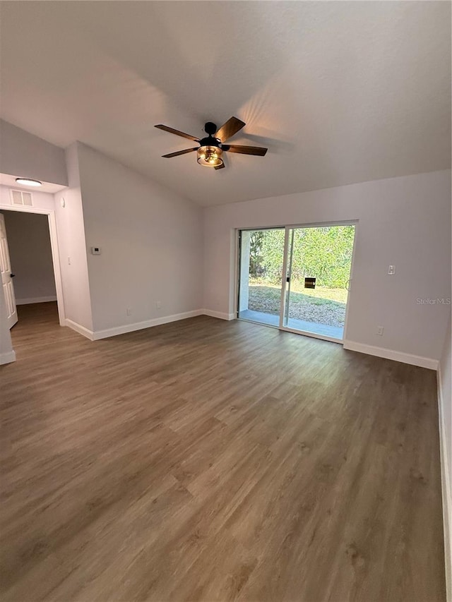 unfurnished living room featuring dark wood-style floors, visible vents, vaulted ceiling, ceiling fan, and baseboards