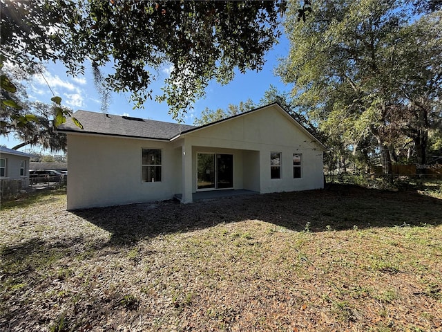 back of property featuring a yard, fence, and stucco siding