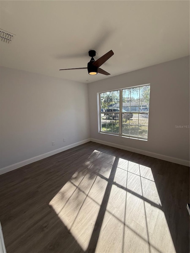 unfurnished room with baseboards, visible vents, and dark wood finished floors