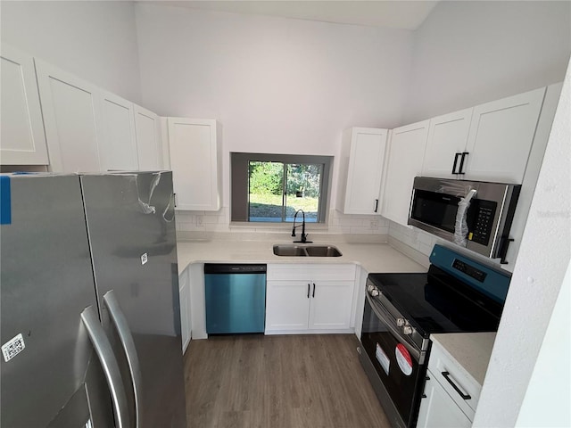 kitchen with stainless steel appliances, white cabinets, light countertops, and a sink