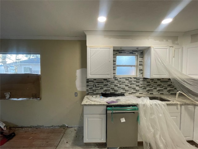 kitchen with white cabinets, light stone counters, ornamental molding, and backsplash