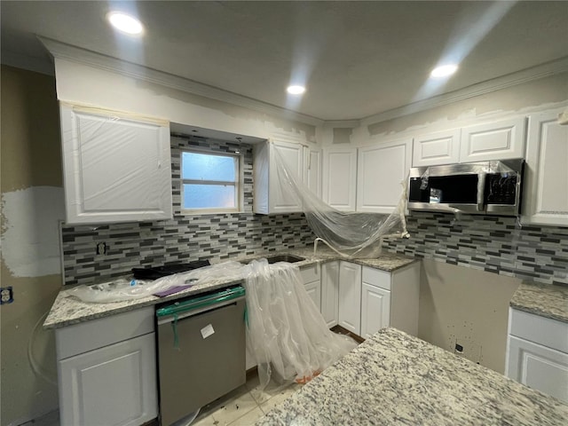 kitchen with white cabinets, light stone countertops, ornamental molding, and appliances with stainless steel finishes