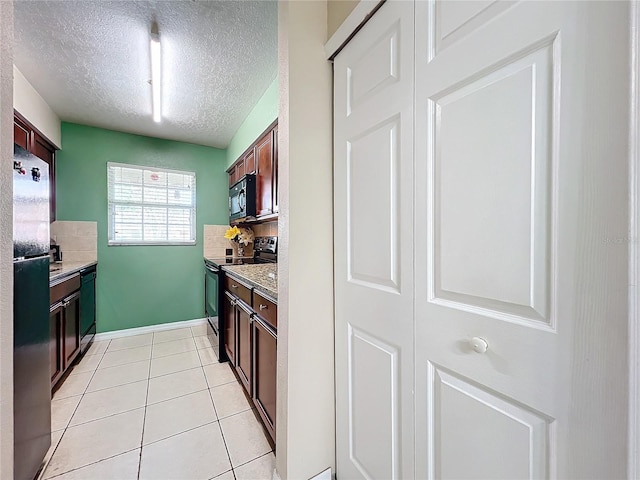 kitchen with backsplash, black appliances, a textured ceiling, light tile patterned flooring, and light stone counters