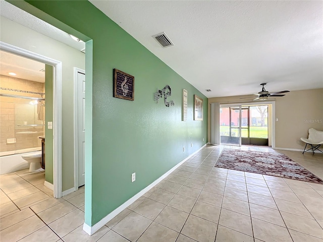 interior space featuring ceiling fan, light tile patterned flooring, and a textured ceiling