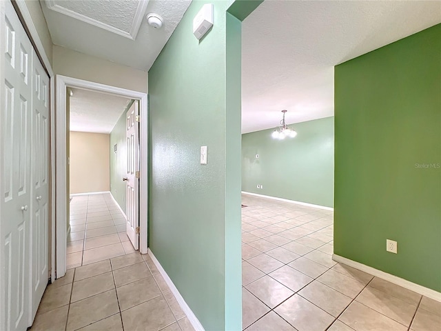 hall featuring light tile patterned flooring, a textured ceiling, and a chandelier