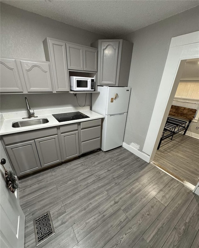 kitchen featuring a textured ceiling, white appliances, gray cabinets, and sink