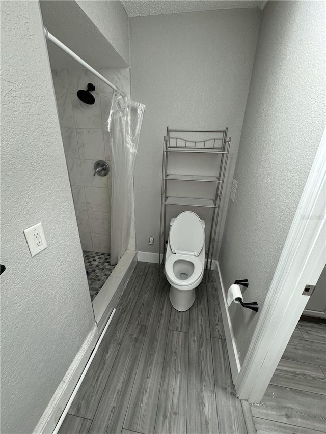 bathroom with hardwood / wood-style flooring, curtained shower, toilet, and a textured ceiling