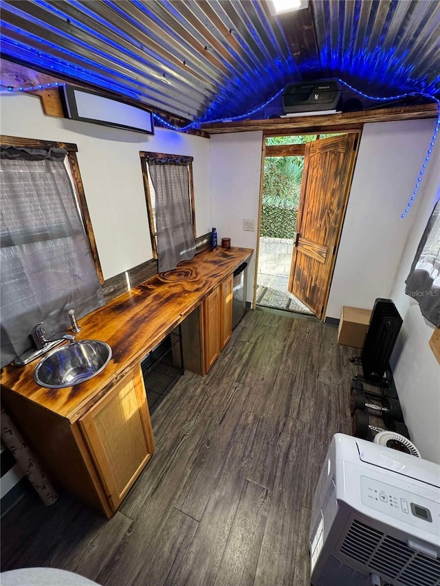 bar featuring dishwasher, sink, wooden counters, dark hardwood / wood-style floors, and heating unit