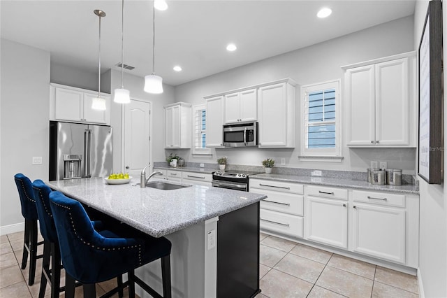 kitchen with visible vents, an island with sink, a sink, appliances with stainless steel finishes, and white cabinetry