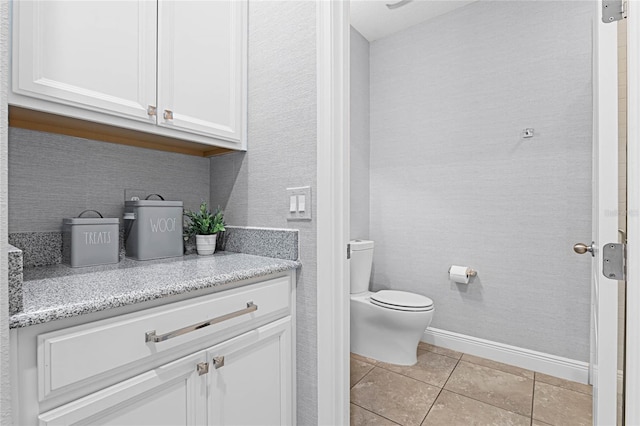 bathroom with tile patterned flooring, toilet, vanity, and baseboards