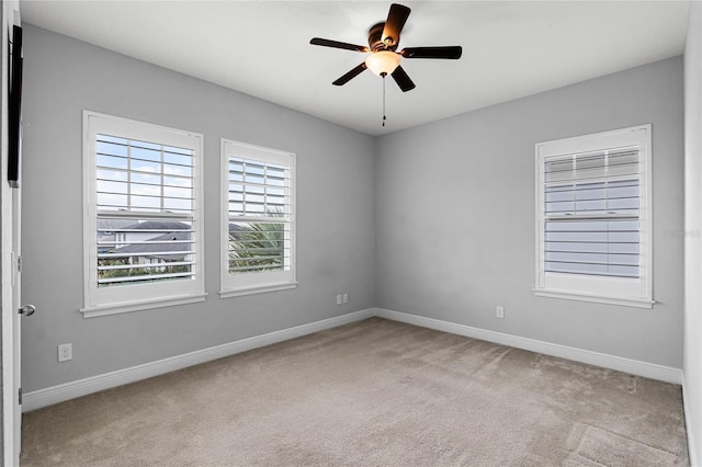 carpeted spare room with ceiling fan and baseboards