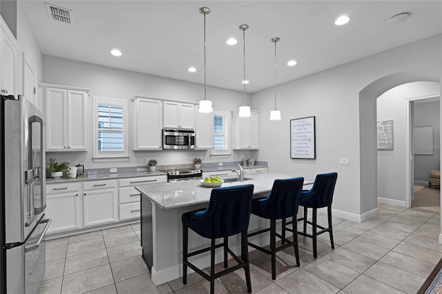 kitchen with arched walkways, recessed lighting, stainless steel appliances, and a sink