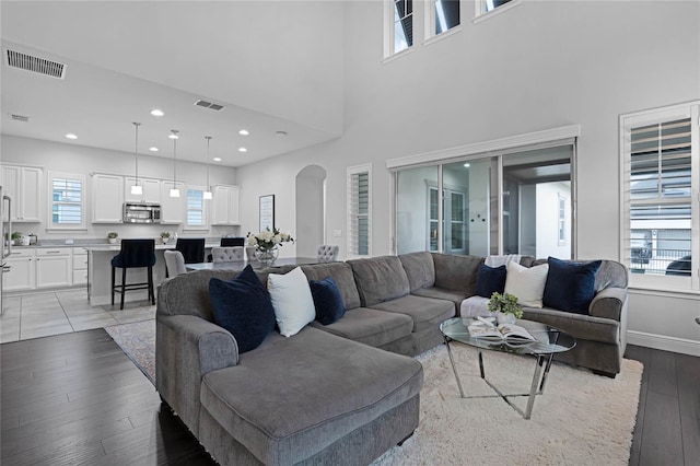 living room featuring visible vents, arched walkways, baseboards, and light wood-style flooring