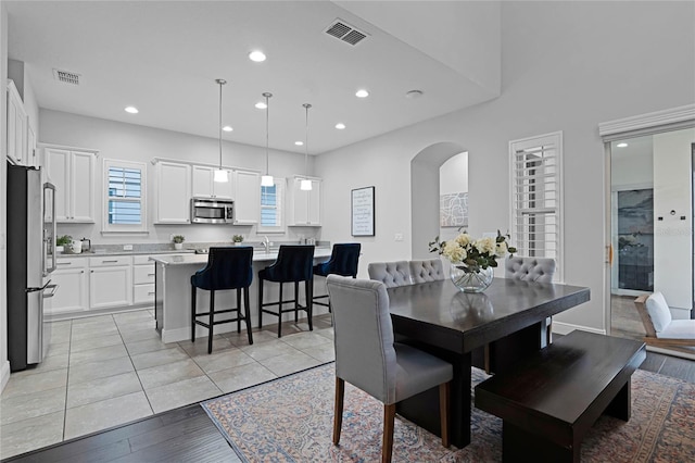 dining area with arched walkways, visible vents, and recessed lighting