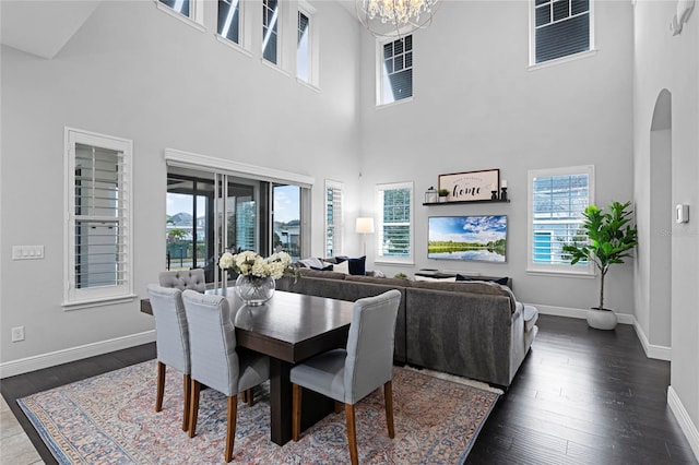 dining room with dark wood finished floors, a healthy amount of sunlight, arched walkways, and a chandelier