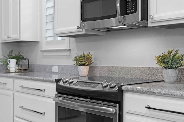 kitchen featuring stainless steel appliances, light stone countertops, and white cabinets