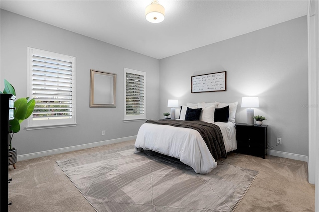 bedroom with baseboards, multiple windows, and light colored carpet