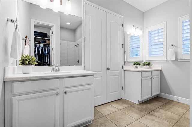 full bathroom featuring tile patterned floors, two vanities, a sink, a shower stall, and baseboards