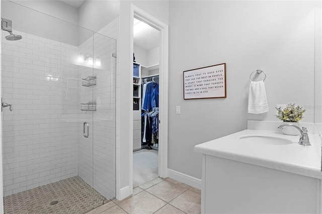 bathroom featuring vanity, baseboards, a stall shower, a spacious closet, and tile patterned floors