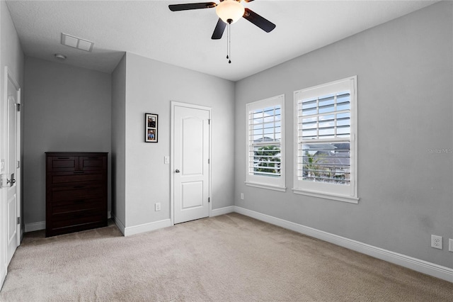 unfurnished bedroom with a ceiling fan, carpet flooring, visible vents, and baseboards