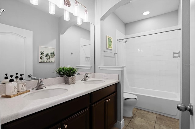 bathroom featuring a sink, toilet, double vanity, and tile patterned flooring