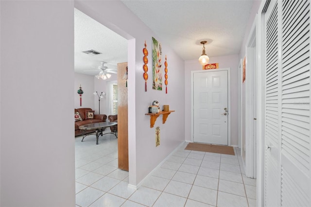 entryway with ceiling fan, light tile patterned floors, and a textured ceiling