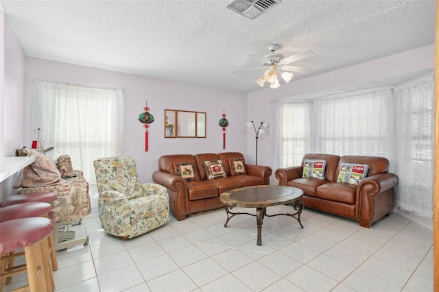 living room featuring ceiling fan, light tile patterned floors, and a textured ceiling