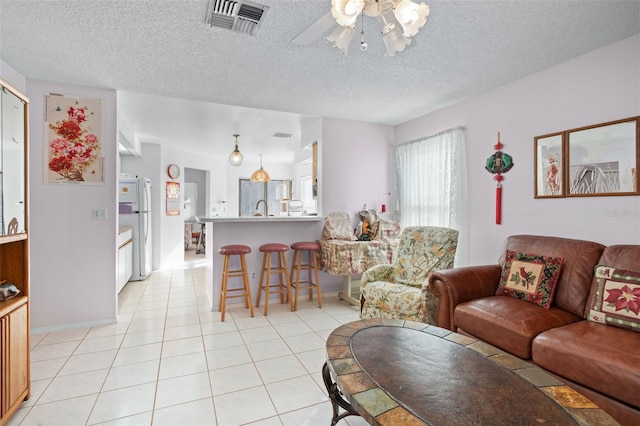 living room featuring light tile patterned floors, a textured ceiling, ceiling fan, and sink