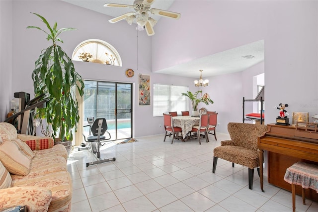 tiled living room with ceiling fan with notable chandelier and a high ceiling