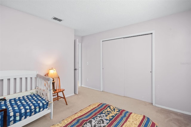 carpeted bedroom with a textured ceiling and a closet