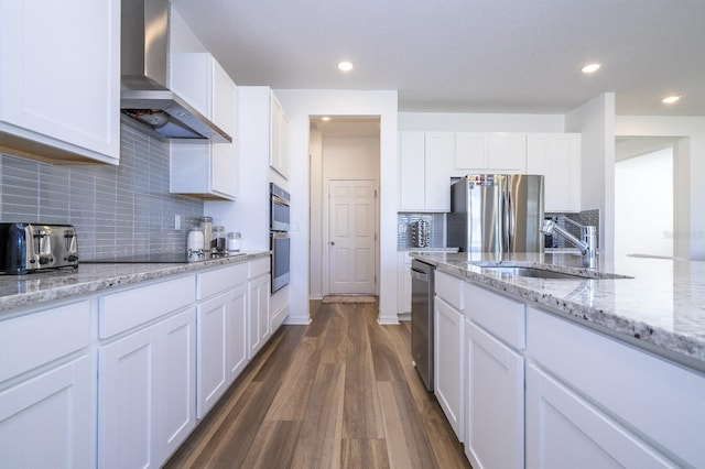 kitchen with white cabinets, dark wood-type flooring, wall chimney range hood, and appliances with stainless steel finishes