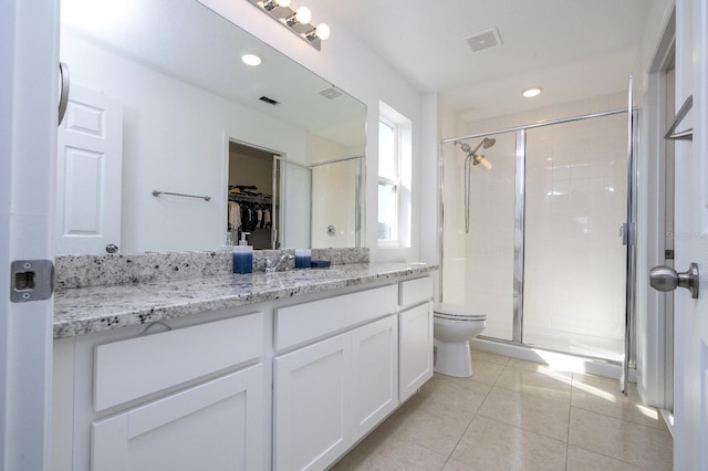 bathroom featuring tile patterned flooring, vanity, toilet, and a shower with shower door