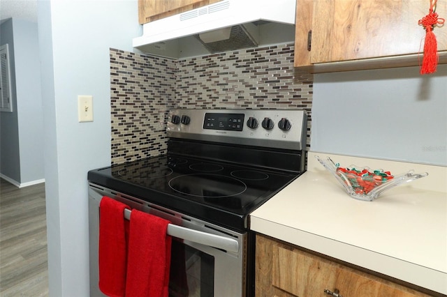 kitchen featuring electric range, decorative backsplash, and extractor fan