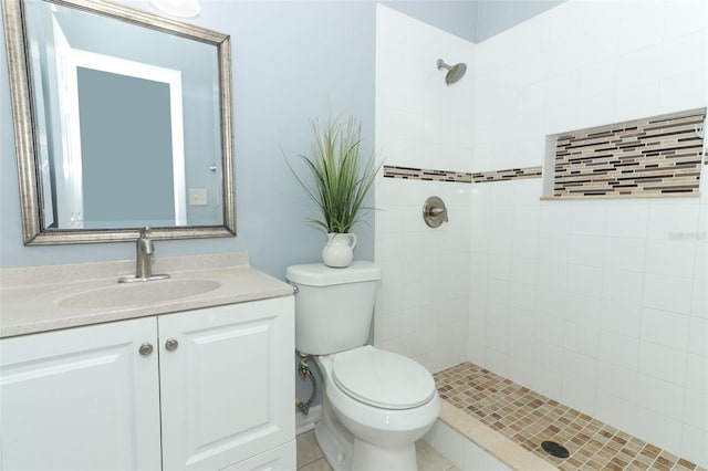 bathroom with vanity, toilet, and tiled shower