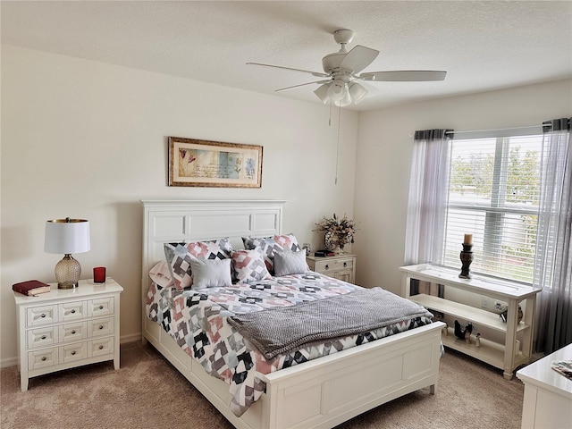 bedroom with light colored carpet, ceiling fan, and a textured ceiling