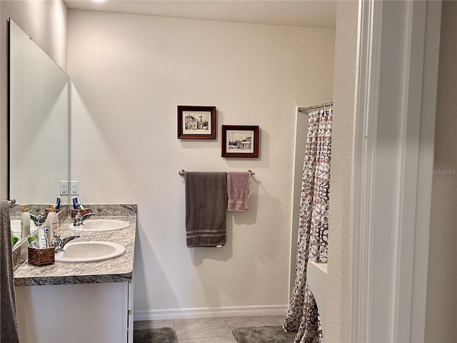 full bathroom with tile patterned flooring, double vanity, baseboards, and a sink