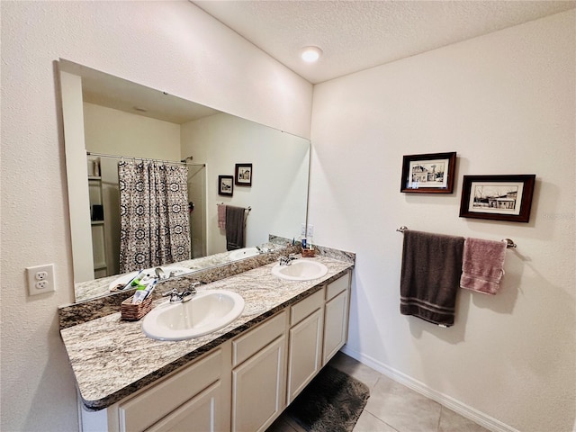 bathroom featuring double vanity, tile patterned floors, a textured ceiling, and a sink