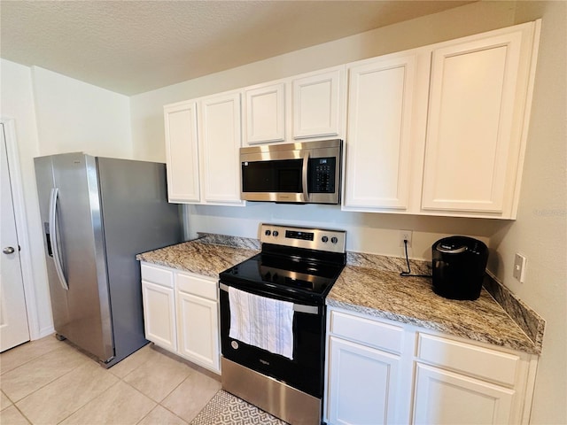 kitchen featuring light tile patterned floors, a textured ceiling, appliances with stainless steel finishes, and white cabinets