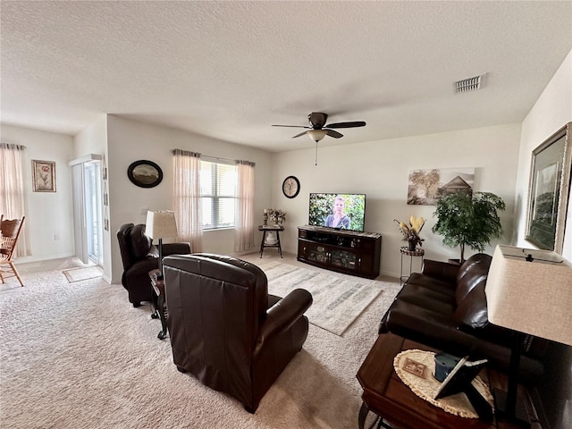 carpeted living room with baseboards, a ceiling fan, visible vents, and a textured ceiling