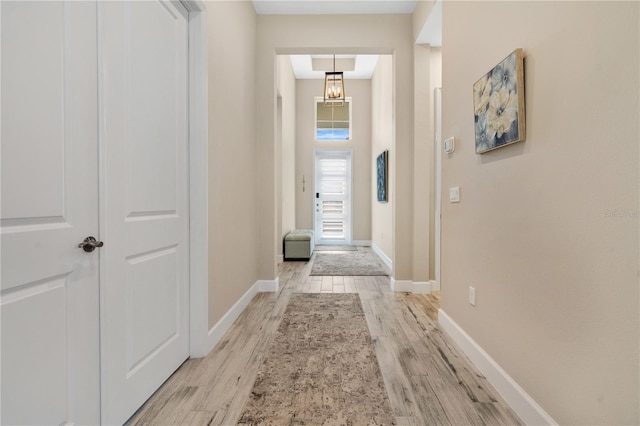 corridor featuring a chandelier and light wood-type flooring