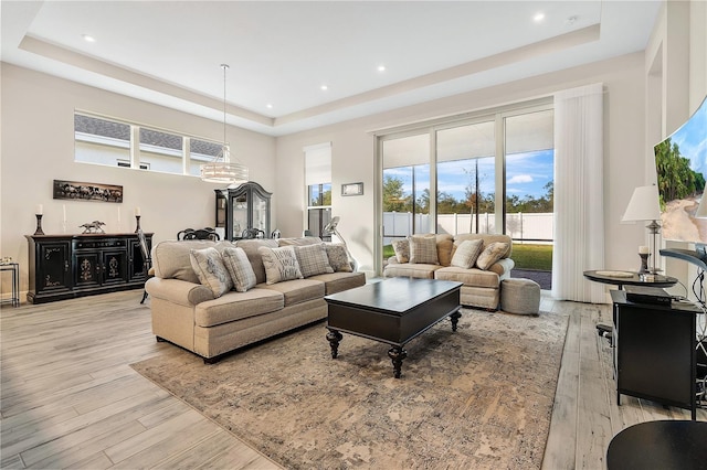 living room featuring a raised ceiling and light hardwood / wood-style flooring