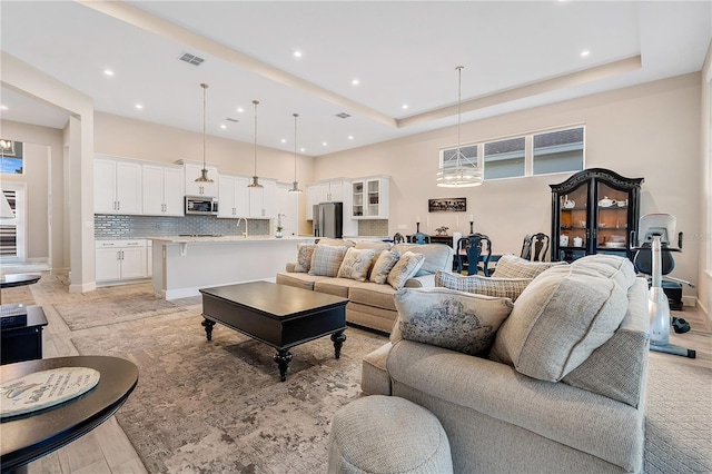 living room with light wood-type flooring and a tray ceiling