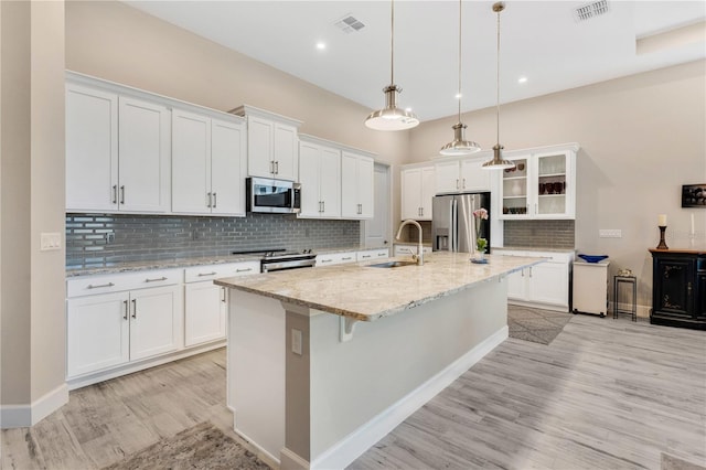 kitchen with white cabinetry, sink, decorative light fixtures, a kitchen island with sink, and appliances with stainless steel finishes