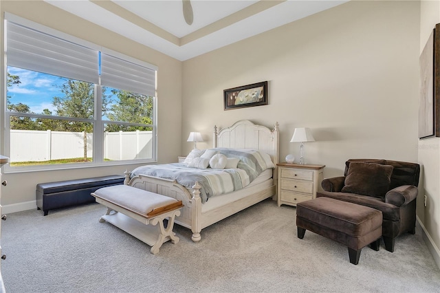 bedroom featuring ceiling fan, a raised ceiling, and light carpet